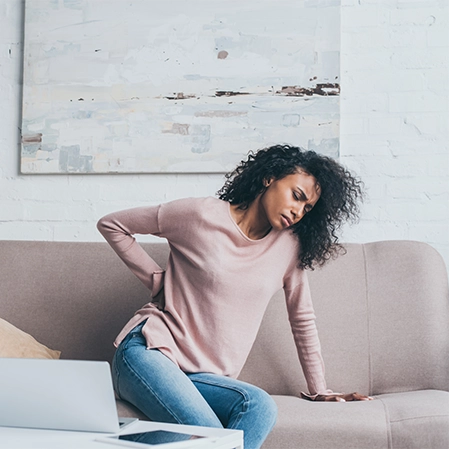 Woman With Back Pain Sitting On Couch